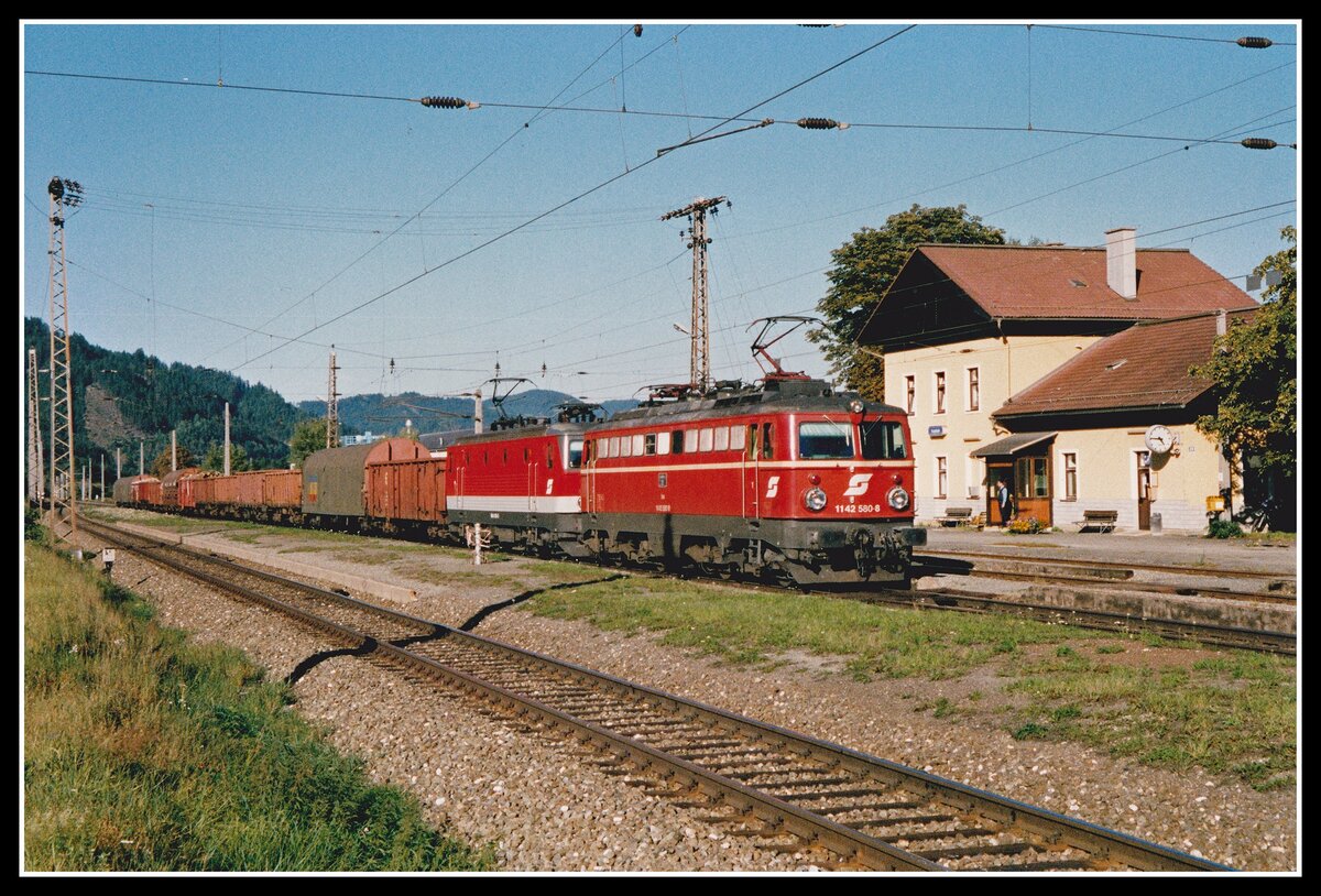 1142 580 + 1044 034 fahren am 18.09.2002 mit einem Güterzug durch den Bahnhof Kraubath.