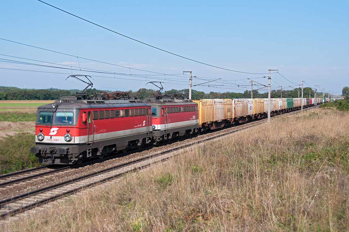 1142 685 und 1142 586 mit einem Hackschnitzelzug zwischen Himberg und Gramatneusiedl, am 13.09.2018.