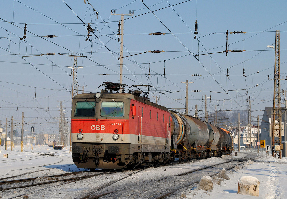 1144 043 mit einem Güterzug bei der Durchfahrt durch Attnang - Puchheim. (20.01.2017)