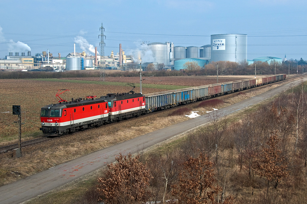 1144 048 und 1144 270, unterwegs vor der Kulisse der Zuckerfabrik in Tulln, in Richtung St. Pölten. Die Aufnahme entstand am 15.02.2015.