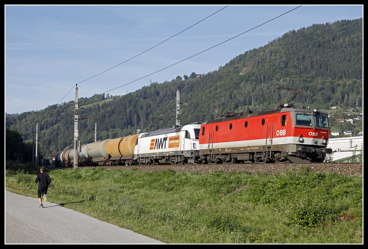 1144 058 und 183 718 ziehen am 20.09.2019 einen Güterzug bei Kapfenberg durchs Mürztal.