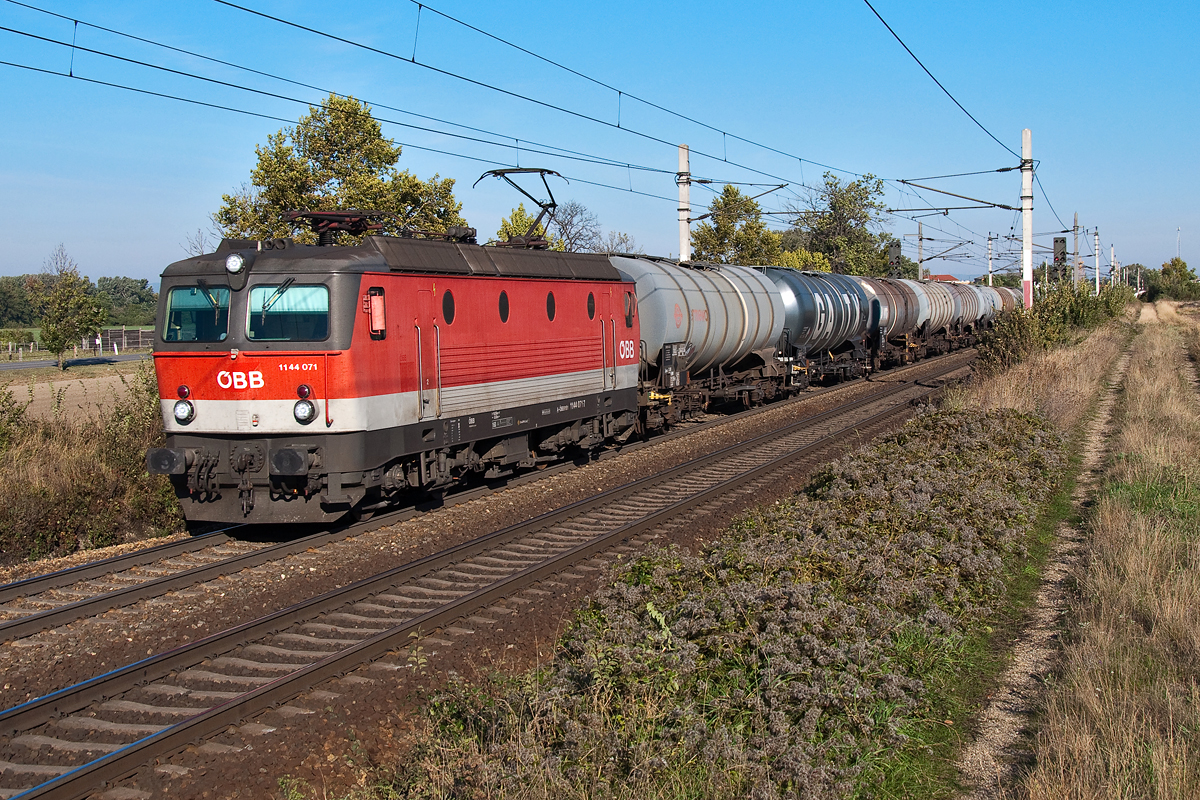 1144 071 ist mit einem Kesselwagenganzzug zwischen Himberg und Gramatneusiedl in Richtung Osten unterwegs. Die Aufnahme entstand am 04.10.2013.