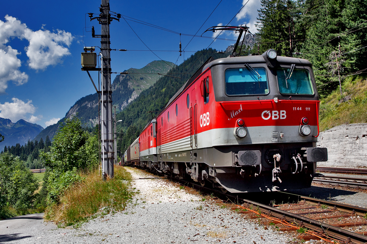 1144 111  Maxl fährt mit einer Schwesterlokomotive mit einem langen gemischten Güterzug in Wald a/A vorüber.Bild vom 22.7.2015