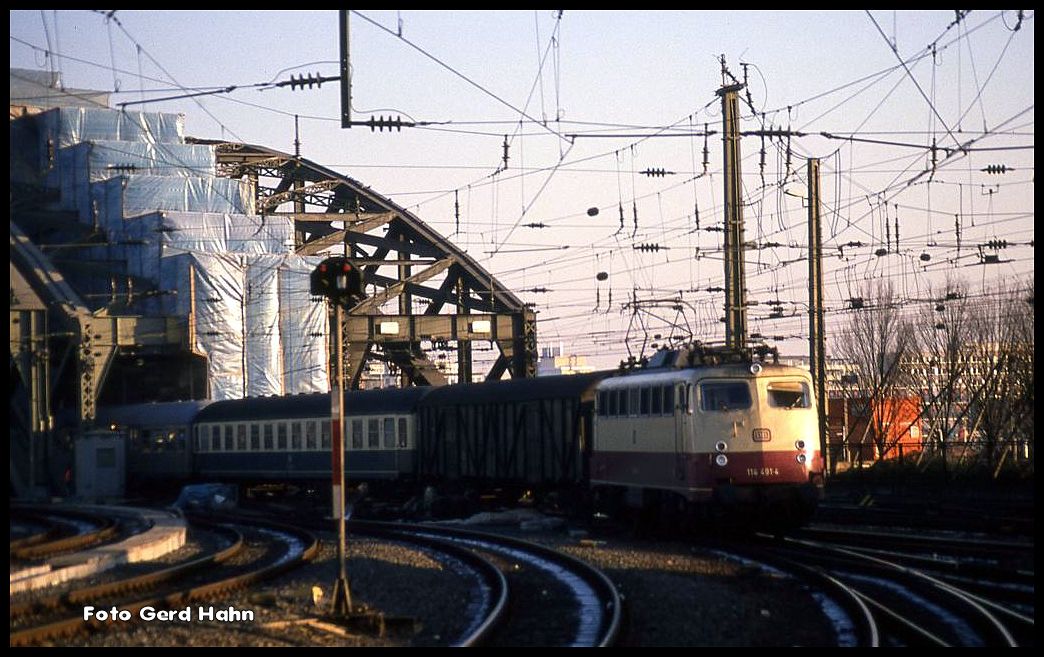 114491 verlässt mit einer bunten Wagengarnitur die Hohenzollern Brücke in Köln und erreicht somit in der letzten Abendsonne am 30.11.1989 den Kölner HBF.