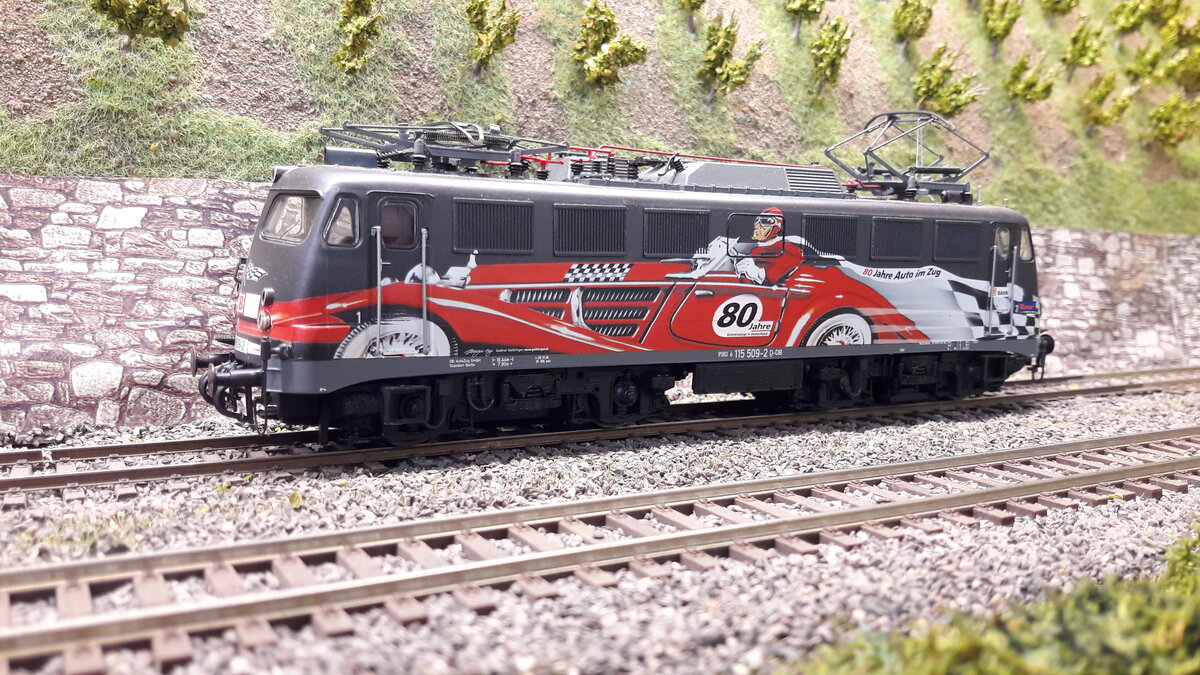 115 509-2 in Sonderlackierung   80Jahre Auto am Zug , vor den Weinbergen in Harrstadt.
Modell Roco 62547
