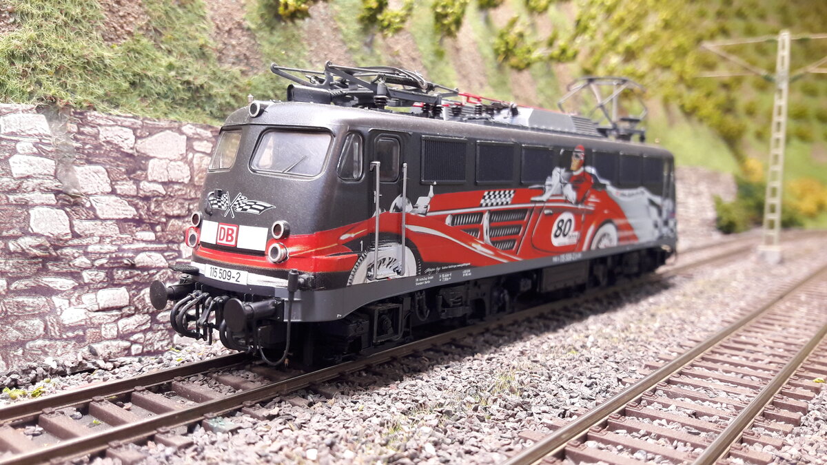 115 509-2 in Sonderlackierung   80Jahre Auto am Zug , vor den Weinbergen in Harrstadt.
Modell Roco 62547