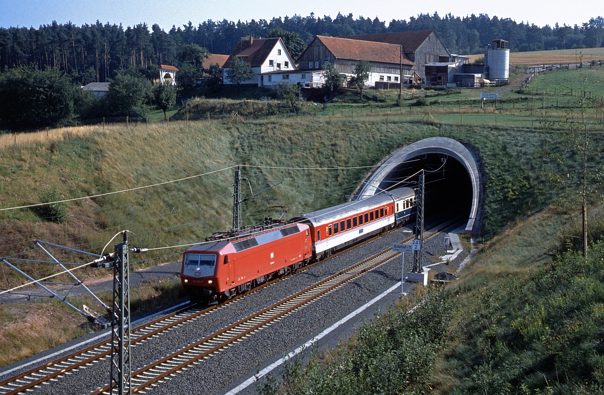 120 103 verlässt den Sulzhoftunnel südlich Fulda in Richtung Norden. Oben am Hof steht ein Protestschild :  Seid dem Tunnelbau ist unser Hof nur noch einen Teller Suppe wert , was darauf hindeutet, das die Gebäude durch Bodenbewegungen (?) in Mitleidenschaft gezogen wurden (6.8.1988).