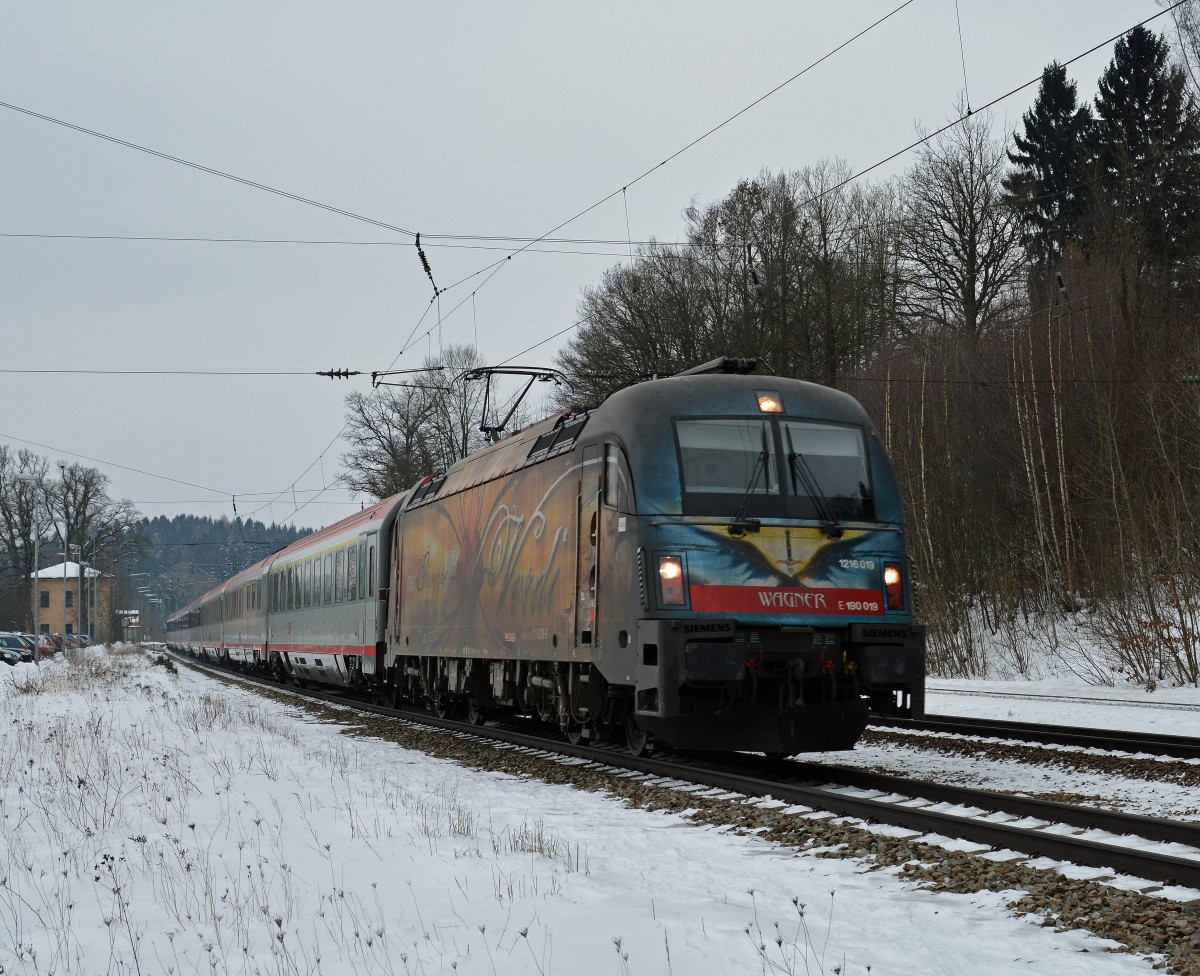 1216 019(Mit Werbung zu Ehren für die zwei im Jahre 1813 geborenen Komponisten Wagner und Verdi)kommt mit dem EC 82 von Innsbruck nach München durch den Bahnhof Assling am 6.2.2015.