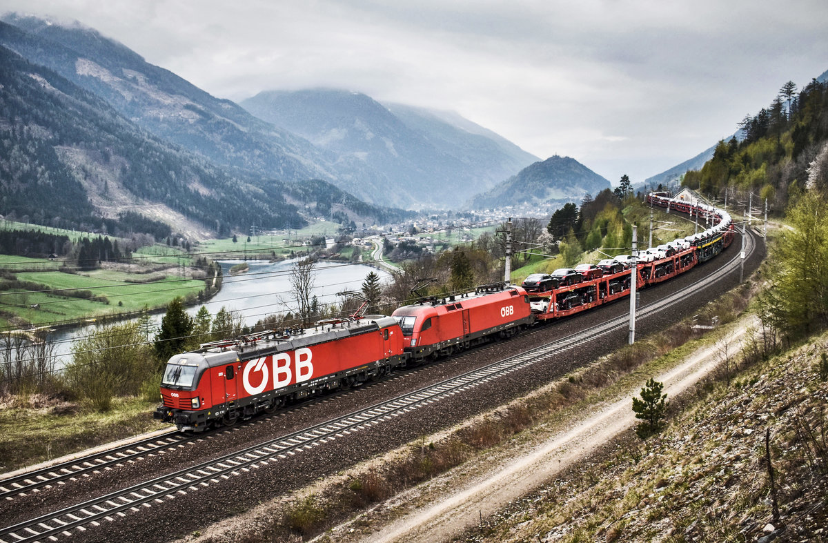 1293 025-3 und 1116 111-6 fahren mit einem Autozug, bei Mühldorf, die Tauernbahn-Südrampe hinunter.
Aufgenommen am 13.4.2019.