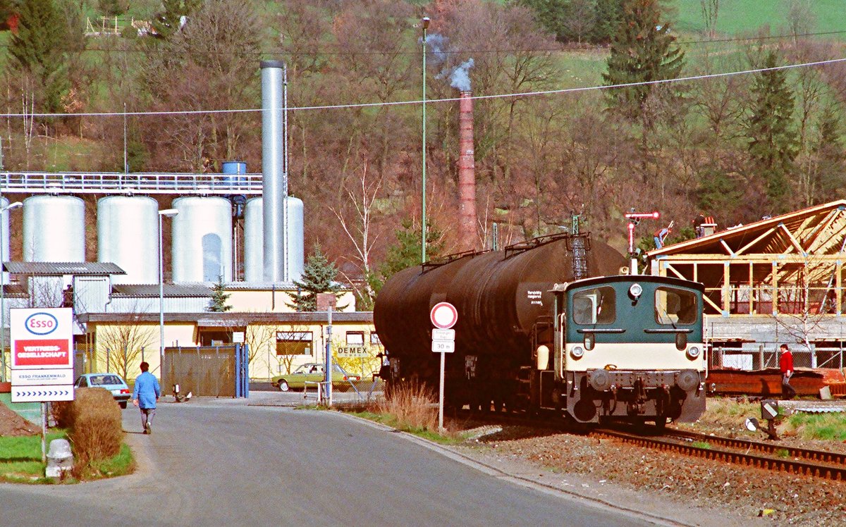 14.04.1988, Rodachtalbahn Kronach - Nordhalben, zu dieser Zeit fand noch Güterverkehr mit Kö III 333 122 zu den Kronacher Industriebetrieben und für Holztransporte auf der gesamten Strecke statt. Das ESSO-Tanklager existiert nicht mehr, der rauchende Schornstein gehört zu einem Mineralölverarbeiter. Rechts ist das zweiflüglige Einfahrtsignal in den Bahnhof Kronach sichtbar.