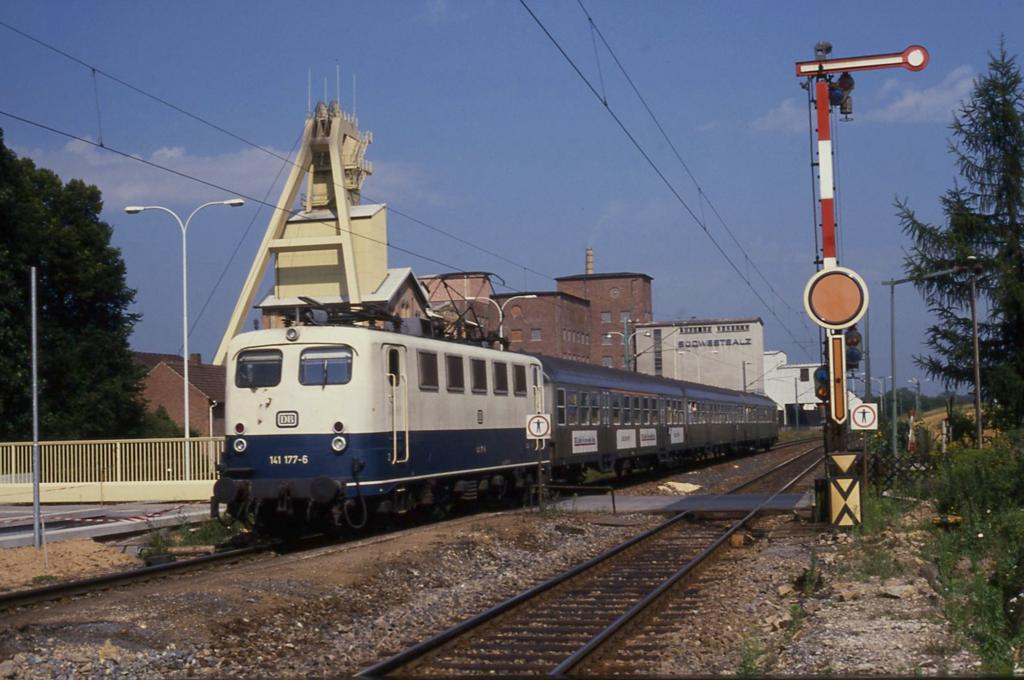 141177 mit E 3379 nach Heilbronn am 15.8.1989 um 11.05 Uhr vor der Kulisse des Salzbergwerks in Bad Friedrichshall Kochendorf.