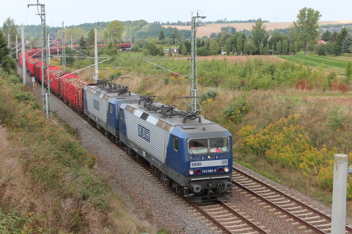 143 286-3 (RBH 106) und 143 191-5 (RBH 104) fahren am 24.09.2013 mit dem Holzzug aus Richtung Werdau nach Plauen zum Entladen, hier zu sehen am Bogendreieck bei Werdau.