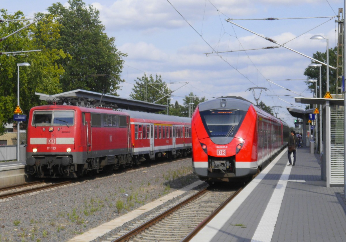 1440 309 bildet den zweiten Teil eines S 8-Zuges Mönchengladbach - Hagen, aufgenommen  beim Halt in Kleinenbroich. Auf dem Gegengleis rauscht 111 113 mit ihrem aus 5 n-Wagen bestehenden RE 4-Verstärker Richtung Aachen vorbei (25.8.15).