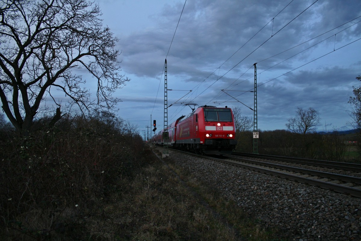 146 112-8 verlie in der Abenddmmerung des 14.02.14 mit einem RE von Offenburg nach Basel SBB den Bahnhof Mllheim (Baden).