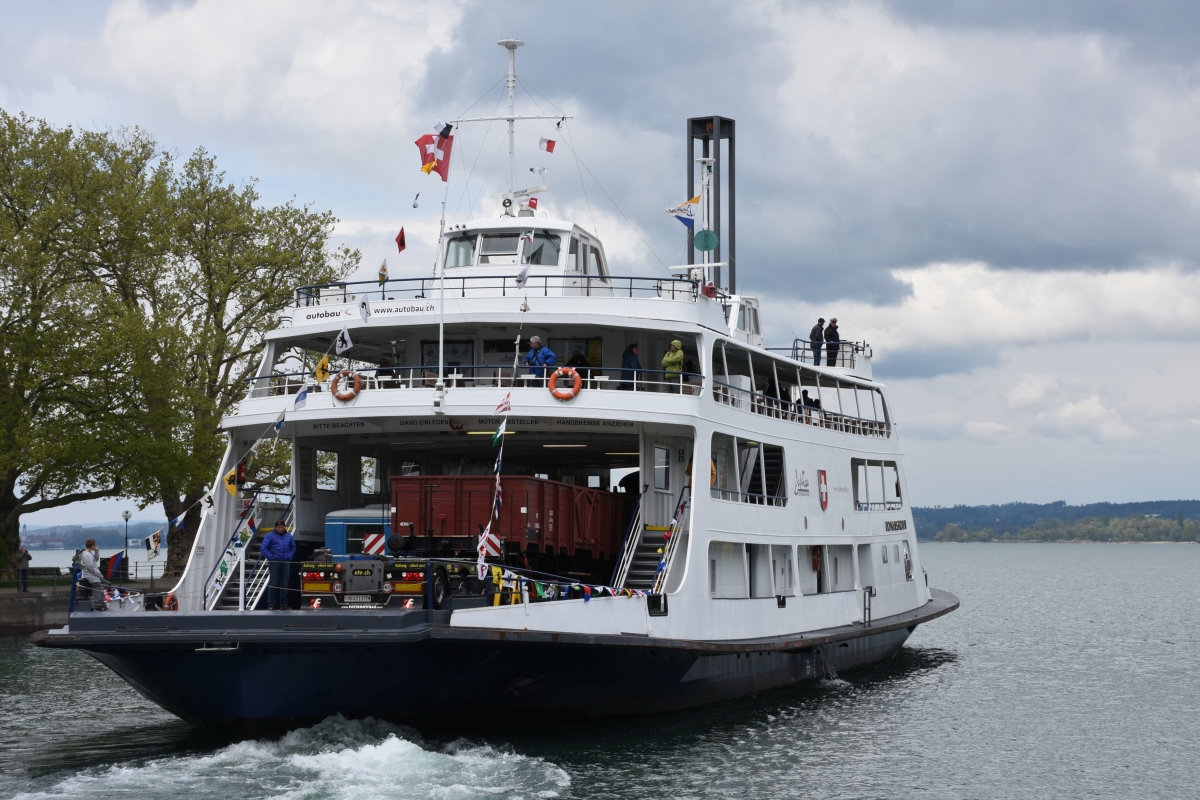 150 Jahre Trajektverkehr am Bodensee (ja, das ist ein Bahnbild!)
Um den Warenverkehr zwischen Deutschland und der Schweiz zu beschleunigen, wurde vor 150 Jahren die erste Trajektlinie zwischen Lindau und Romanshorn über den Bodensee in Betrieb genommen. Zur Erinnerung steuerte die MF „Romanshorn“ am (04. und) 05.05.2019 sämtliche ehemaligen Trajektbahnhöfe/-häfen an. Da es heute keine einzige Fähre mehr am Bodensee gibt, auf die Eisenbahnwaggons verladen werden könnten, mussten die historischen Waggons per Tieflader auf die MF „Romanshorn“ gekarrt werden. Hier verlässt sie den Hafen Bregenz.
