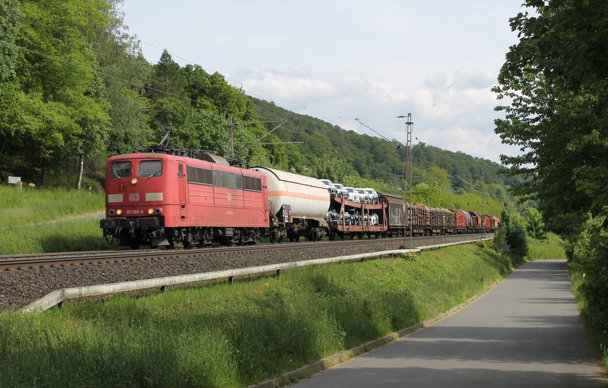 151 086-6 der Deutschen Bahn, in einem schönen orientrot, zieht einen gemischten Güterzug am 21.05.2016 durch das Leinetal vorbei am kleinen Dorf Erzhausen. 