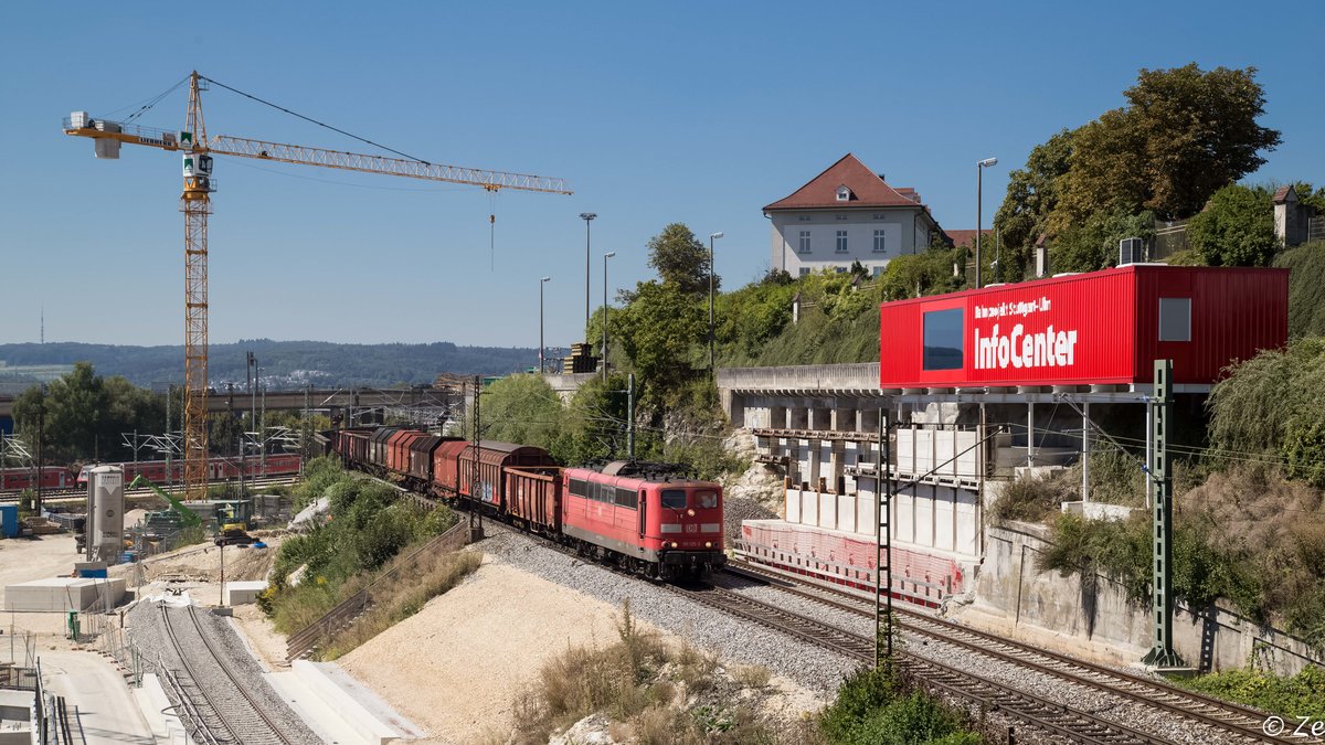 151 125-2 mit einem Stahl- / Schrottzug bei der Ausfahrt aus dem Ulmer Rbf in Richtung Stuttgart. Der rote Kasten rechts, ist ein Info-Container für das Projekt NBS (Stuttgart) Wendlingen-Ulm. Direkt darunter kann man die Baustelle für das Portal des Albabstiegstunnels erkennen. August 2016.
