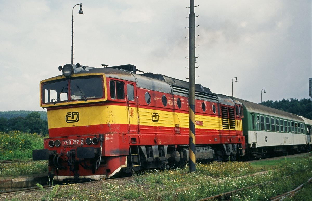 16. August 1996, in Tschechien bei Klatovy (?), Diesellok CD 750 217 mit Reisezug der CD. Die ČSD-Baureihe T 478.3 (ab 1988 Baureihe 753) ist eine dieselelektrische Universallokomotive der ehemaligen Tschechoslowakischen Staatsbahn (ČSD). Dem markanten Äußeren mit den blendfreien Führerständen verdanken die Lokomotiven ihren Spitznamen Taucherbrille bzw. Brillenschlange (Brejlovec). Die ab 1991 modernisierten Lokomotiven wurden als Reihe 750 eingeordnet.
