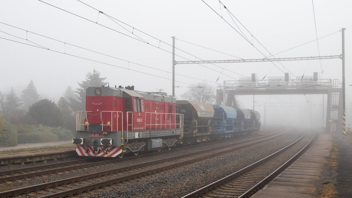 16. November 2018 in Zelenice nad Bilinou. 742 201-7 kam mit ihrem kurzen Schotterzug durch die Nebelwand. 