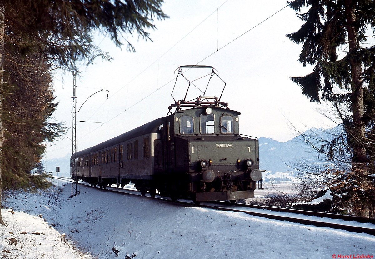 169 002-3 ist im Dezember 1978 zwischen Murnau und Bad Kohlgrub unterwegs. Zu diesem Zeitpunkt war die 1909 an die Lokalbahn Aktien-Gesellschaft als LAG 2 gelieferte und 1938 nach der Verstaatlichung von der Deutschen Reichsbahn als E 69 02 eingereihte Lok die älteste im Einsatz stehende Lokomotive der DB. Heute gehört sie dem DB Museum Nürnberg.