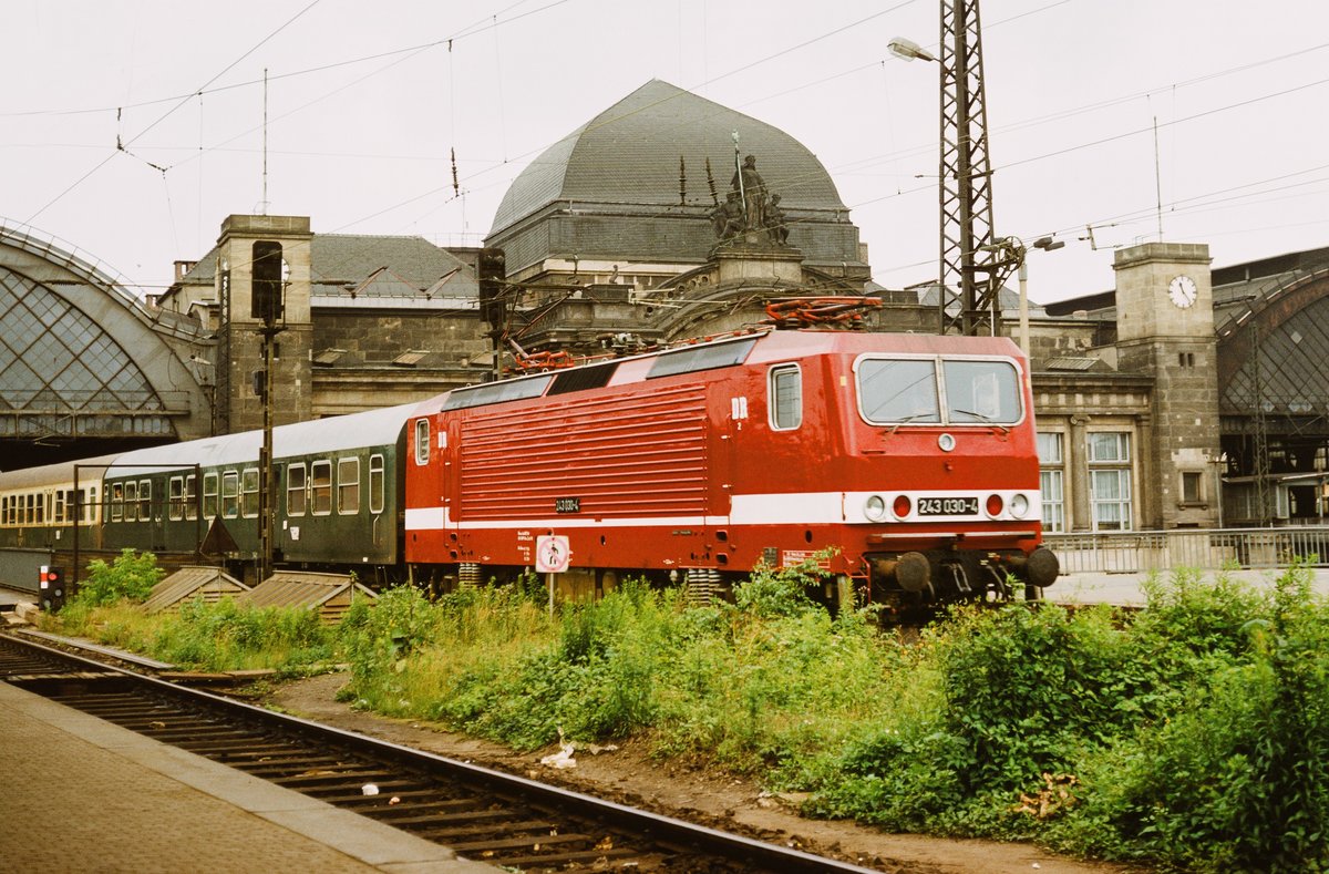16.Juni 1986, Dresden Hauptbahnhof. Weder die Lok noch ihr Personal können ahnen, dass schon bald nicht nur die  2  einer  1  weichen wird, sondern auch die mächtige Kuppelhalle mitsamt dem ganzen Bahnhof eine Generalsanierung und die vordergründige  Bienenweide  die totale Auslöschung erfahren wird. Bei dem Zug könnte es sich um den  Vindobona  handeln, er fuhr etwa um die an der Uhr angezeigte Zeit von Dresden weiter über Prag nach Wien. 