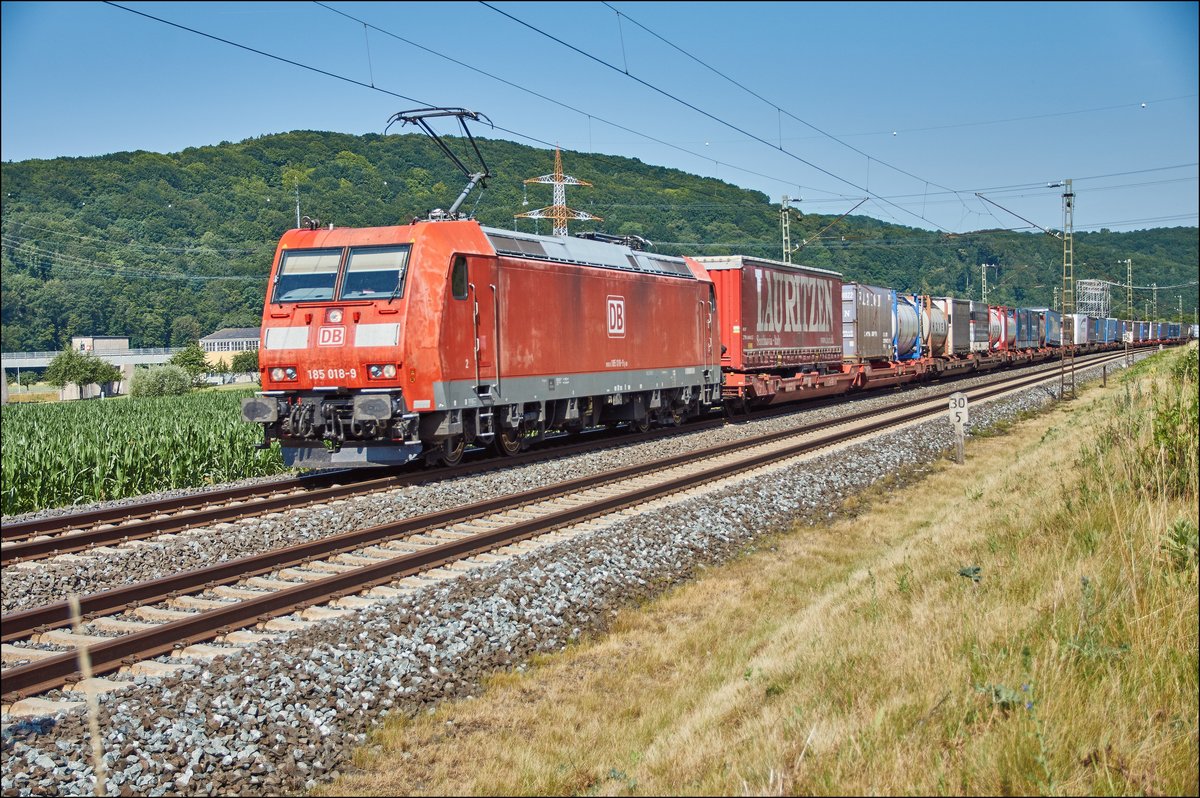 185 018-5 ist mit einen Aufliegerzug bei Harrbach am 05.07.2017 in Richtung Süden unterwegs.