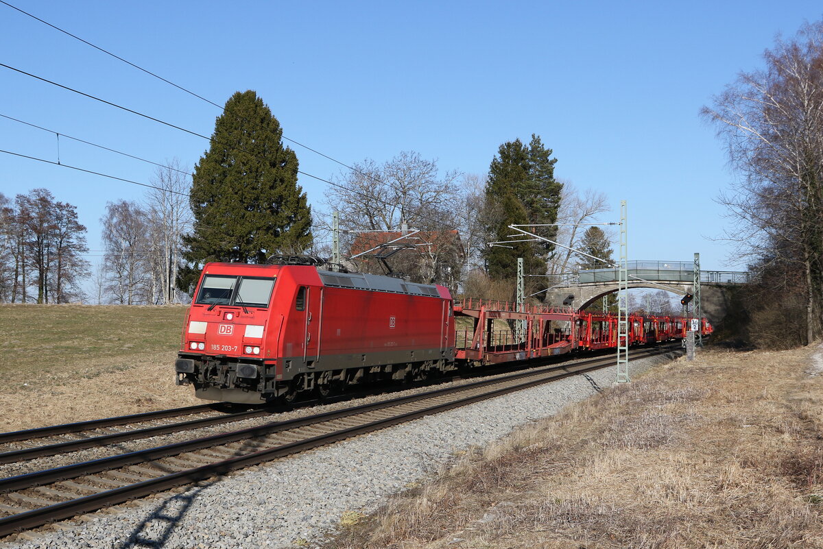 185 203 war am 8. März 2022 mit einem Autozug bei Übersee am Chiemsee in Richtung München unterwegs.