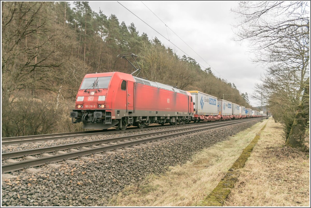 185 216-9 mit einem Aufliegerzug in Richtung Norden im Haunetal am 09.02.2022.