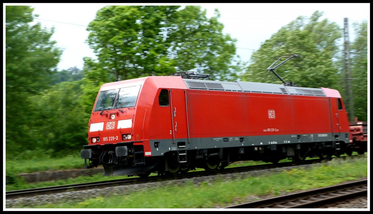 185 229 schießt am 28.5.15 mit einigen Flachwagen über die Nord-Süd-Strecke Richtung Süden. 
Aufgenommen bei Kerzell, südlich von Fulda. 