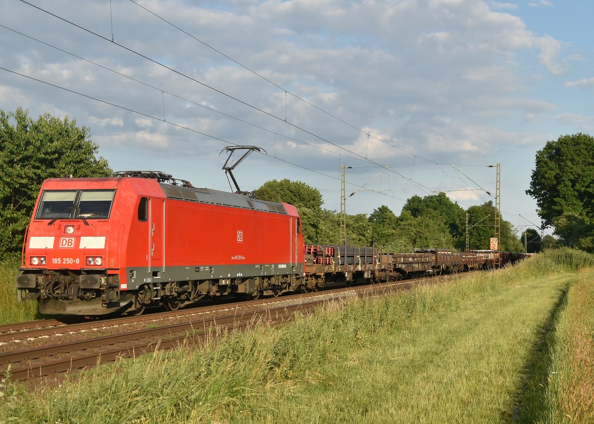 185 250-8 mit einem Stahl beladenen Wagen und mehreren Schienenwagen am Haken aus Neuss kommend gen Osterath bei Kaarst Broicherseite fahrend. 17.6.2019