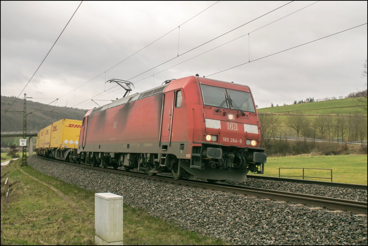 185 264-9 am 09.02.2022 mit einem DHL-Containerzug bei Hermannspiegel unterwegs.