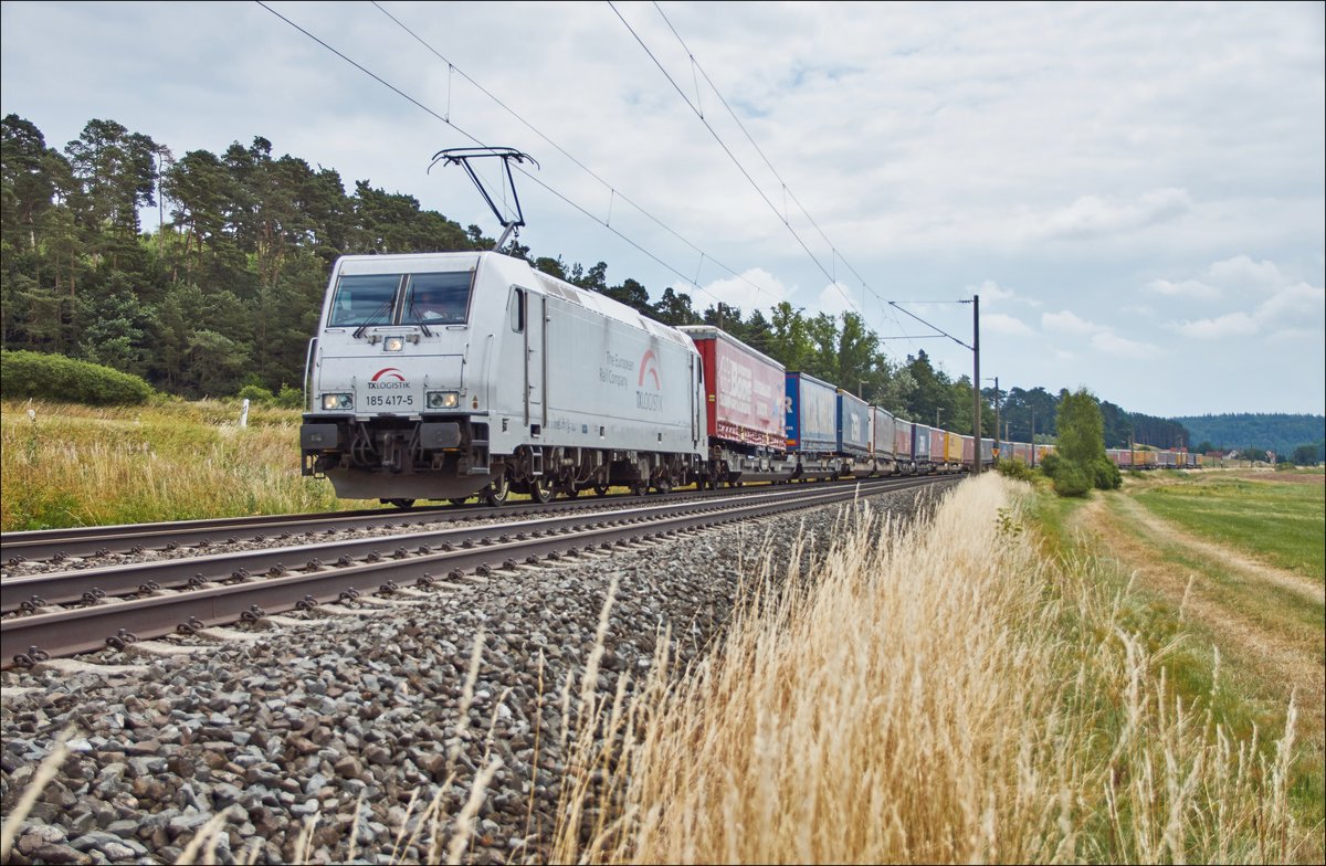 185 417-5 ist mit einen Aufliegerzug in Richtung Würzburg unterwegs,gesehen am 11.07.2018 bei Dörfle.