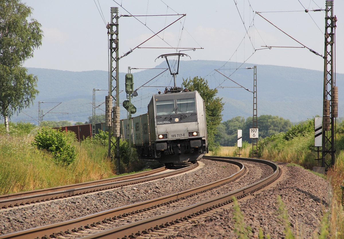 185 717-6 legt sich mit ihrem Containerzug vor Wehretal-Reichensachsen in Fahrtrichtung Süden in den Gleisbogen. Aufgenommen am 17.07.2013.