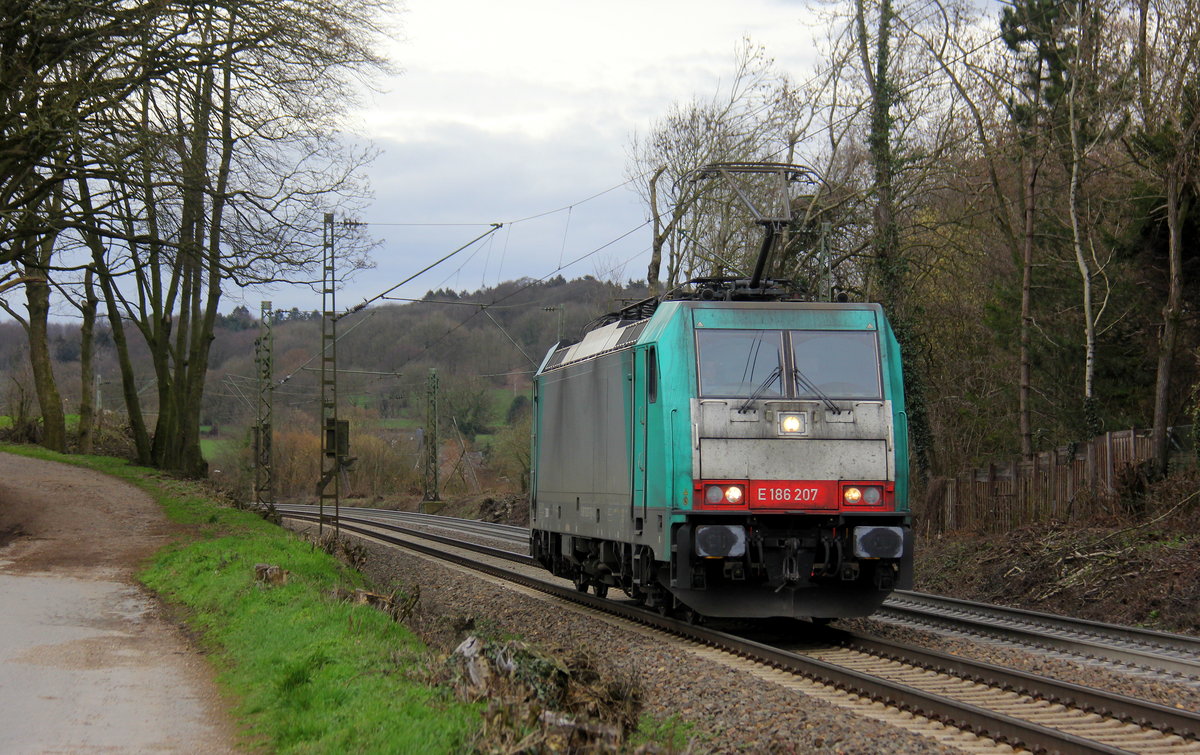 186 207 von der Rurtalbahn-Cargo kommt als Lokzug aus Genk-Goederen(B) nach Aachen-West(D)  und fährt die Gemmenicher-Rampe herunter nach Aachen-West. 
Aufgenommen an der Gemmenicher-Rampe am Gemmenicher-Weg auf dem Montzenroute.
Bei Sonne und Regenwolken am Nachmittag vom 6.3.2019.