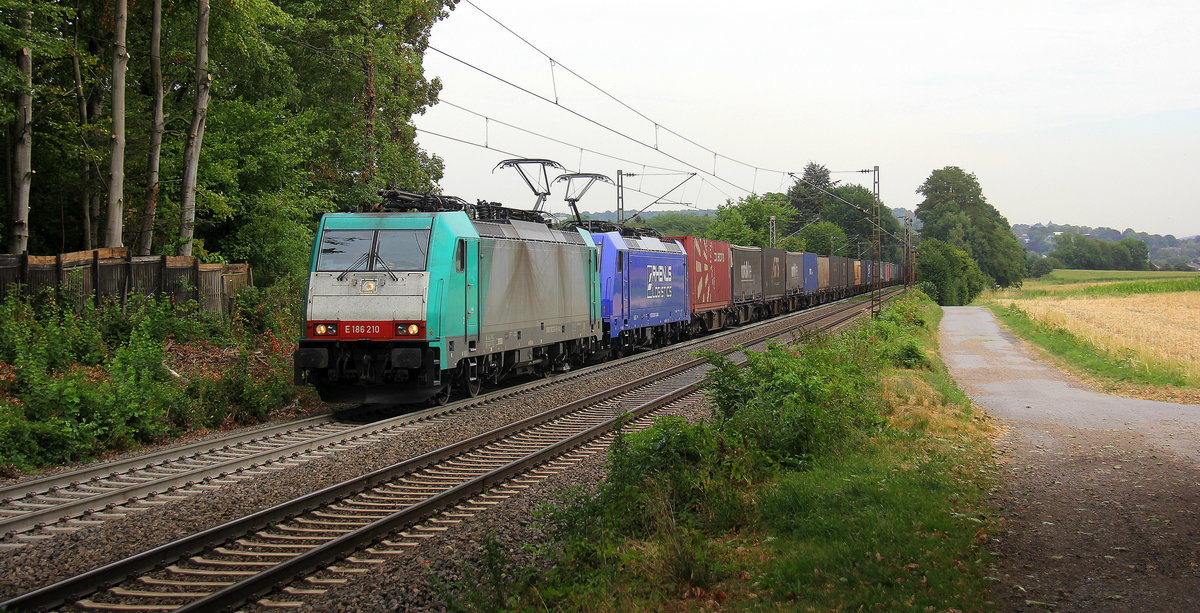 186 210 von Crossrail und 186 269-7 von Rhenus-Logistik kommen die Gemmenicher-Rampe hochgefahren aus Richtung Aachen-West mit einem  GTS-Containerzug aus Piacenza(I) nach Zeebrugge-Ramskapelle(B) und fahren in Richtung Gemmenicher-Tunnel,Botzelaer(B),Gemmenich(B),Nouvelaer(B),Moresnet(B),Moresnet-Chapelle(B),Montzen(B). Aufgenommen an der Montzenroute am Gemmenicher-Weg. 
Bei Wolken am Mittag vom 1.8.2018.