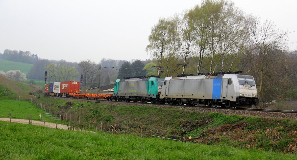 186 424-8 und die Cobra 2841 beide von Lineas kommen aus Richtung Montzen/Belgien mit einem langen KLV-Containerzug aus Genk(B) nach Trieste-Campo-Marzio(I) und fahren die Rampe nach Aachen-West hinunter. 
Aufgenommen von einem Weg in Reinartzkehl. 
Am Nachmittag vom 9.4.2019.