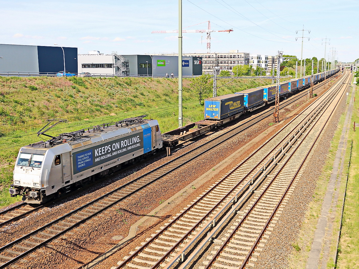 186 436-2 mit einem Containerzug durchfährt Schönefeld in Brandenburg an der Unterführung der Hans-Grade-Straße am 21. Mai 2020.