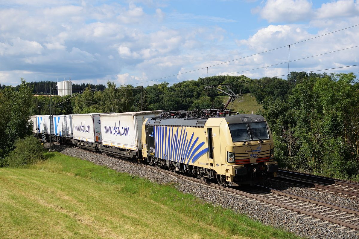 193 777 fährt am 25. Juni 2018 mit offener Tür bei Westerstetten über die Schwäbische Alb Richtung München. Am Haken hat sie viele ekol Sattelauflieger.