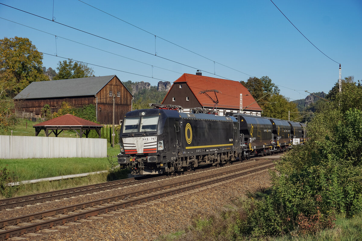 193 797 mit schönen schwarzen, farblich gut zur Lok passenden Waggons in Richtung Tschechien fahrend am 09.10.2024 am Fachwerkhaus neben dem in Fahrtrichtung 3. Rathener Bahnübergang.