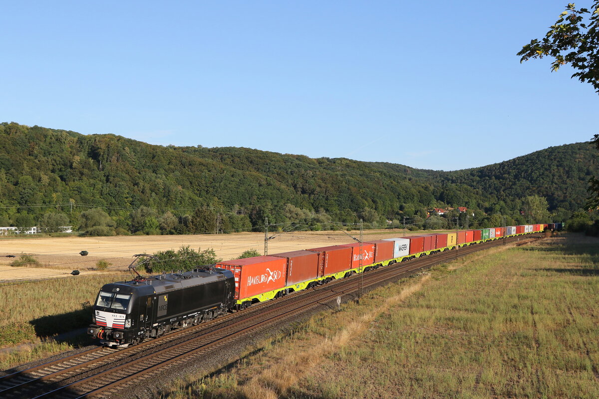 193 874 mit einem Containerzug aus Gemünden kommend am 8. August 2022 bei Harrbach am Main.