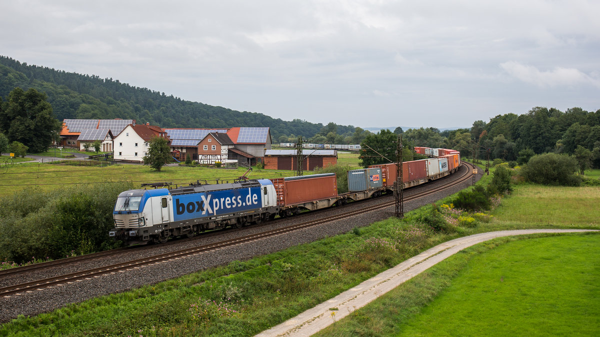 193 883 von boxxpress fährt mit einem Containerzug bei Hermannspiegel in Richtung Fulda, aufgenommen am 10. August 2017.