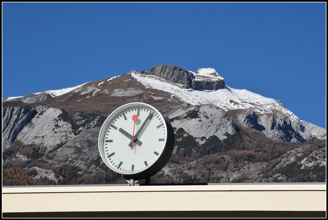 1944 entwarf Hans Hilfiker die typische Schweizer Bahnhofsuhr zuerst ohne Sekundenzeiger. Erst später wurde die Uhr mit dem roten Sekundezeiger versehen, der immer zu vollen Minute 1,5 Sekunden stehenbleibt bis zum Minutensprung. So ziert weithin sichtbar eine solche Uhr auch den Churer Bahnhof, mit Blick hinauf zum Felsberger Calanda 2697m. (15.11.2018)