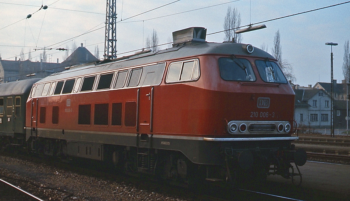 1970/71 stellte die DB 8 Diesellokomotiven der Baureihe 210 in Dienst, die weitgehend der Baureihe 218 entsprachen, zusätzlich jedoch eine Gasturbine erhielten, die bei Bedarf zugeschaltet werden konnte. Nach mehreren Ausfällen wurden die Turbinen 1979 ausgebaut. Im Dezember 1975 wurde die 218 006-3 im Lindauer Hauptbahnhof vor einem Schnellzug aufgenommen. Die Lok wurde am 21.12.1970 beim Bw Kempten in Dienst gestellt und nach dem Ausbau der Gasturbine am 04.12.1980 in 218 906-6 umnummeriert. Am 18.05.2004 wurde sie beim Bw Braunschweig z-gestellt und am 08.11.2006 ausgemustert.