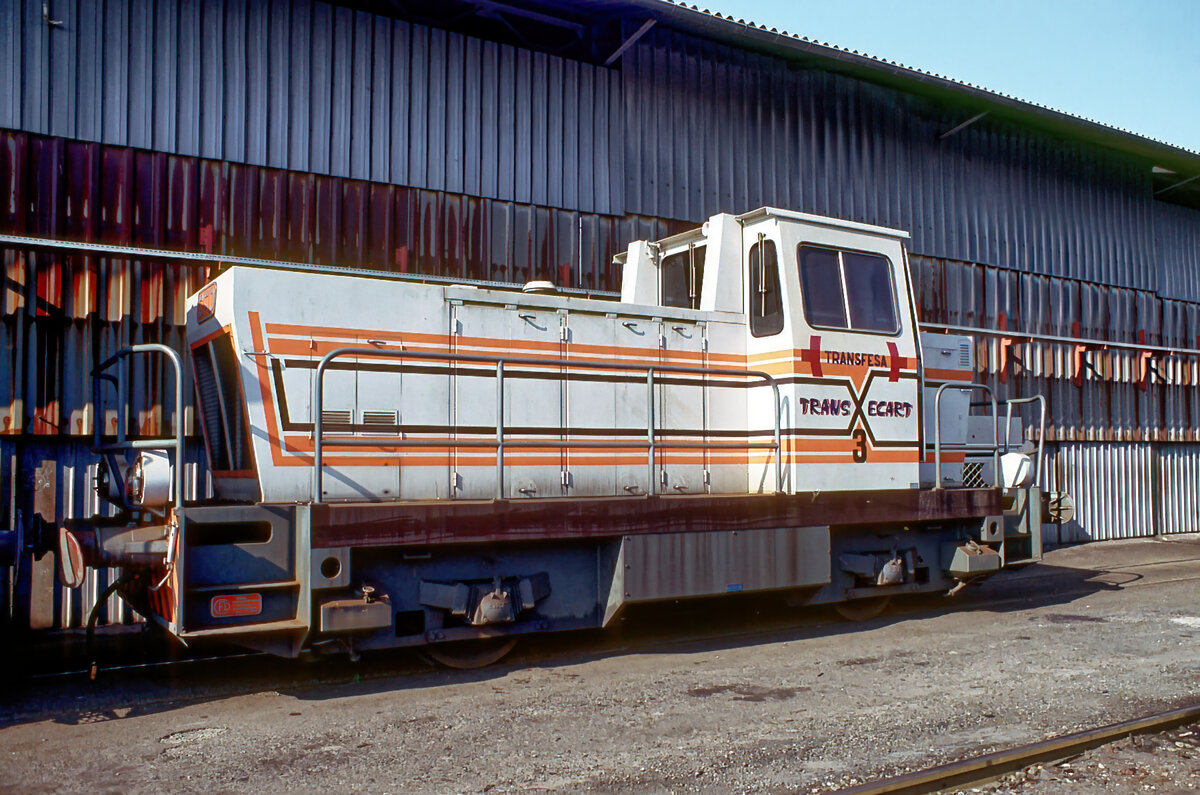 1983 hatte ich auf Empfehlung eines mir bekannten Spediteurs die einzigartige Gelegenheit, die Umspuranlage/Radsatzwechselanlage des spanischen Unternehmens Transfesa für Güterwagen von der spanischen Breitspur auf die Normalspur oder umgekehrt im französischen Grenzort und Eisenbahnknotenpunkt Cerbère bei laufendem Betrieb zu besichtigen und zu fotografieren. Die abgebildete Rangierlok 3 des französischen Lokherstellers CFD hat die einzige Aufgabe, die umzuspurenden Güterwagen in die Halle zum Achswechsel und wieder herauszuschieben.
