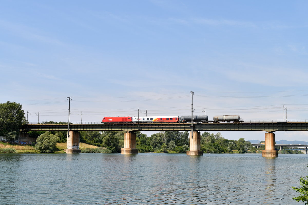 2016 027-2 mit einem Hilfszugwagen, sowie 2 Kesselwagen, am 19.07.2019 auf der Donaubrücke in Wien-Stadlau