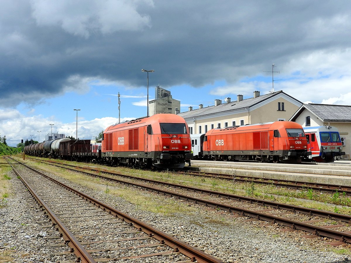 2016 064-5 mit GZ75855, und 2016 063-7 mit R5973, unter der herannahenden Gewitterwolke über dem Bhf. Ried; 160616