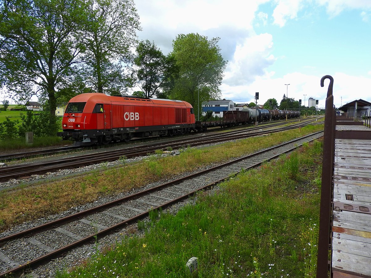 2016 064-5 zieht GZ75855 aus dem Bhf. Ried, während am Gleisstutzen Flachwagen für Panzerbeladung bereitstehen; 160616