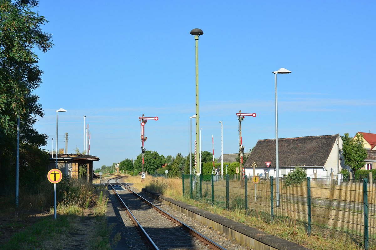 2018 war in Elsnigk die Welt der Eisenbahn noch in Ordnung. Blick auf die Ausfahrsignale in Richtung Köthen sowie Bahnsteig und im Hintergrund den Bahnübergang. Heute ist hier ESTW, ein Inselbahnsteig sowie ein elektronischer Bahnübergang. Die Stellwerke gingen im April 2019 außer Betrieb.

Elsnigk 30.07.2018