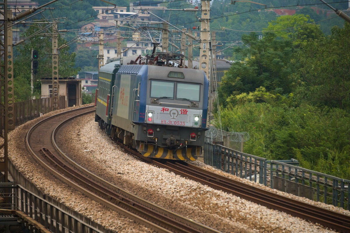 2025.09.21, HXD3C 0535 of CR GuangZhou (ChangSha Depot), tackling the curve on bridge over the old BeiJing-GuangZhou Line's subgrade. CR still retain the tradition of running slower (120kph vmax) passenger service over extreme long distance, conveniently allow them throw freight loco such as HXD3C geared at lower vmax on these service.
---
2025.09.21, HXD3C 0535 der CR GuangZhou (Depot ChangSha) bewältigt die Kurve auf der Brücke über dem alten Gleisbett der Strecke Peking-Guangzhou. Die CR hält weiterhin an der Tradition fest, den Personenverkehr über extrem lange Strecken mit geringerer Geschwindigkeit (120 km/h vmax) zu betreiben, was es ihr ermöglicht, Güterlokomotiven wie die HXD3C mit niedrigerer vmax für diesen Dienst einzusetzen.