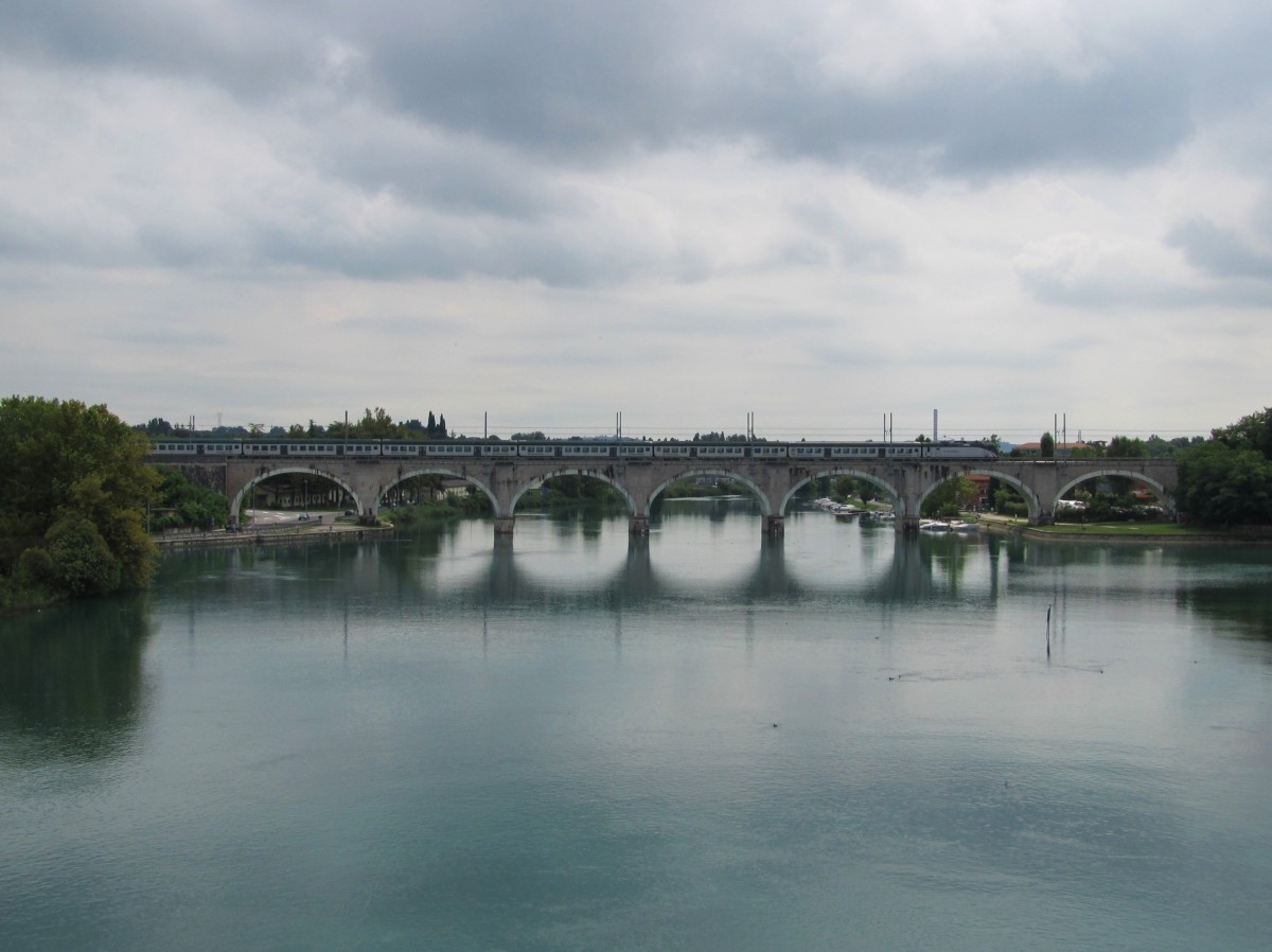 20.8.2014 13:04 Trenord E.464 XXX mit einem Regionalzug (R) aus Verona Porta Nuova nach Milano Centrale überquert auf einer Brücke einen Seitenarm des Gardasees kurz nach Peschiera del Garda.